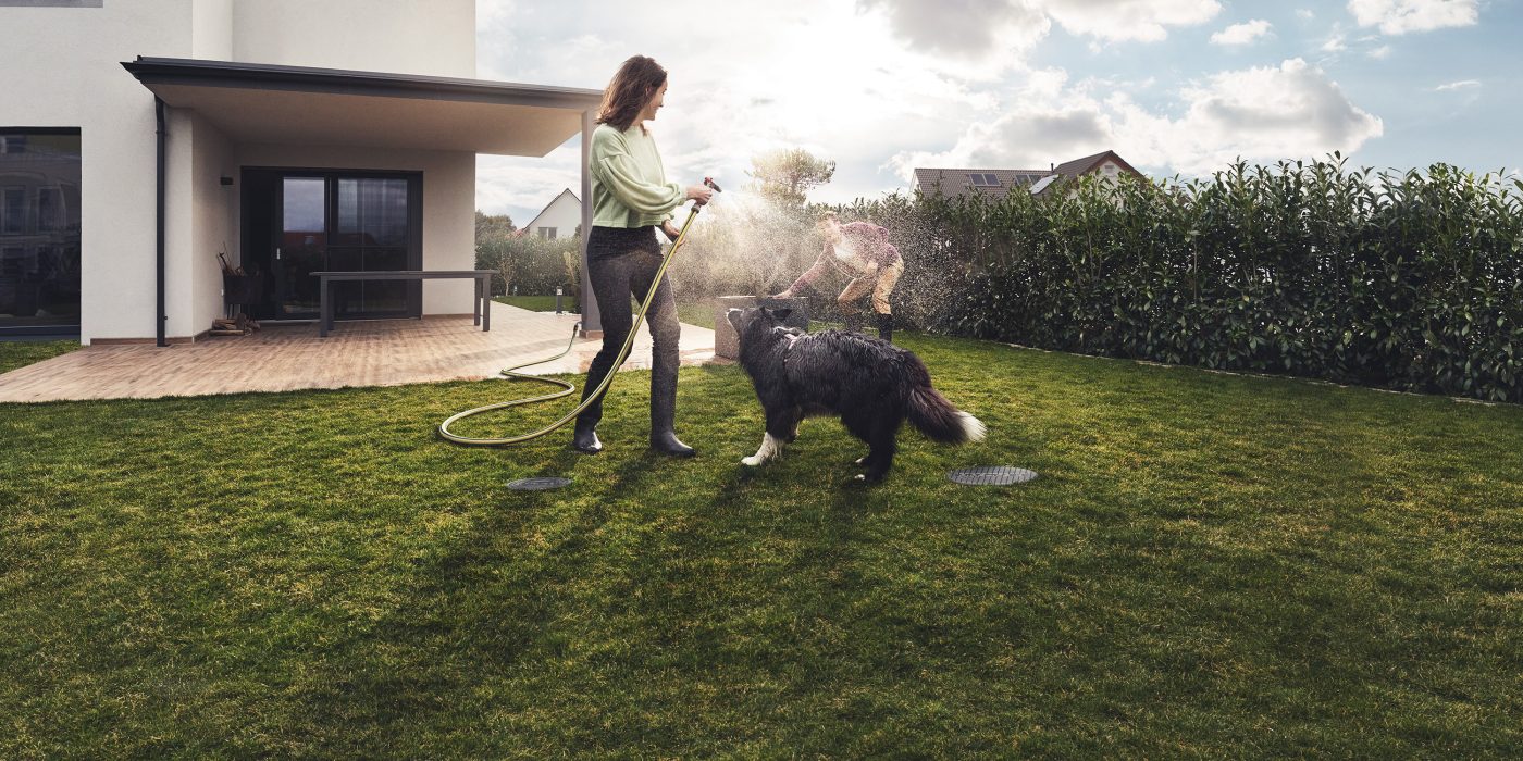 Djevojka koja zalijeva psa s vodom