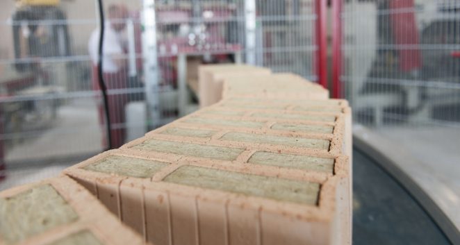 Insulation filled clay blocks on conveyor belt leaving filling station at production plant Haiding