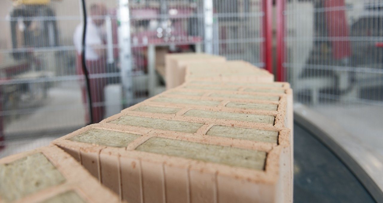 Insulation filled clay blocks on conveyor belt leaving filling station at production plant Haiding