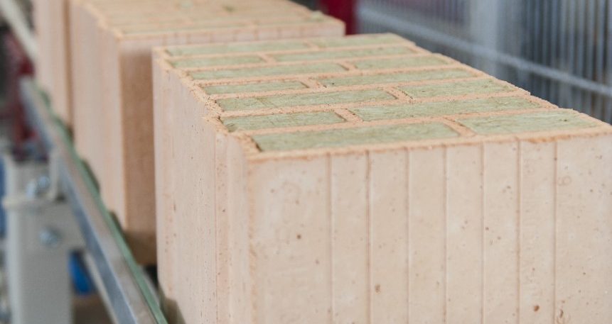 Insulation filled clay blocks on conveyor belt leaving filling station at production plant Haiding