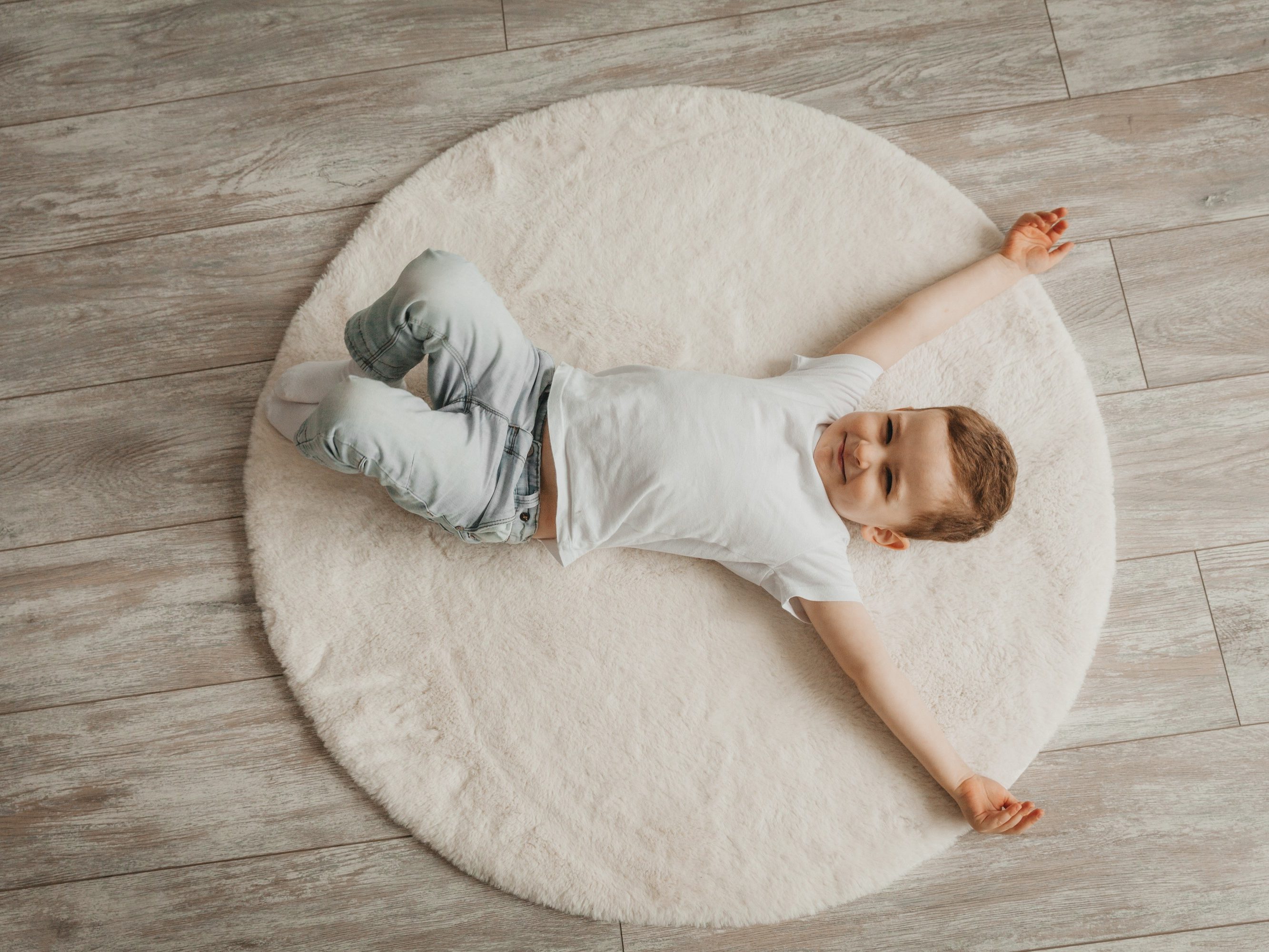 Dječak leži na podu i uživa u podnom grijanju